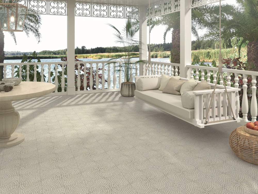 Bright outdoor verandah overlooking water, styled with white furniture and featuring Mikron Delos patterned tiles in a soft neutral mosaic design.